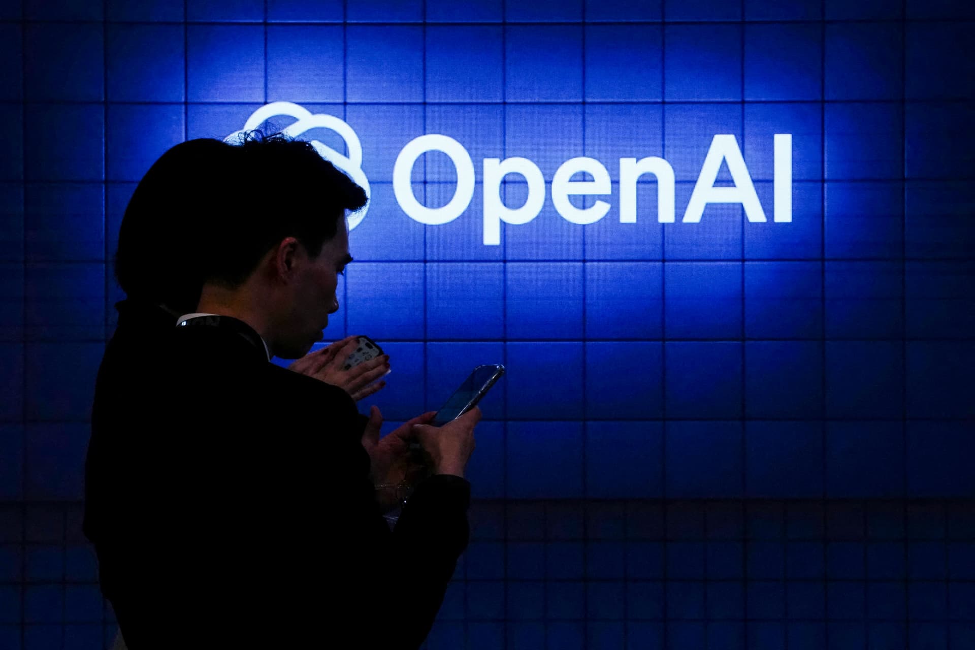 A visitor looks at their phone next to an Open AI logo during the Mobile World Congress, the telecom industry's biggest annual gathering, in Barcelona on Feb. 26, 2024. (Pau Barrena/AFP via Getty Images)