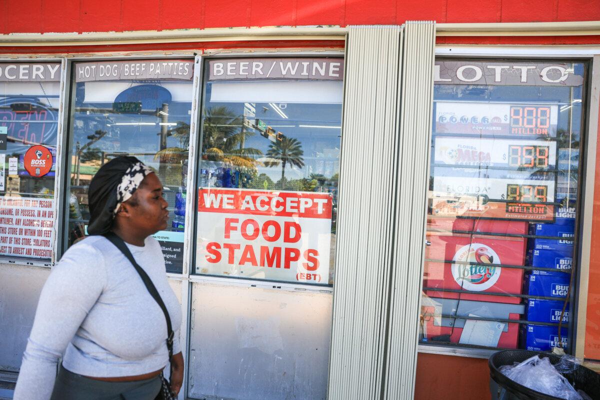 A woman walks by a sign advertising the acceptance of food stamps, in Miami, Fla., on Oct. 31, 2025. (Joe Raedle/Getty Images)