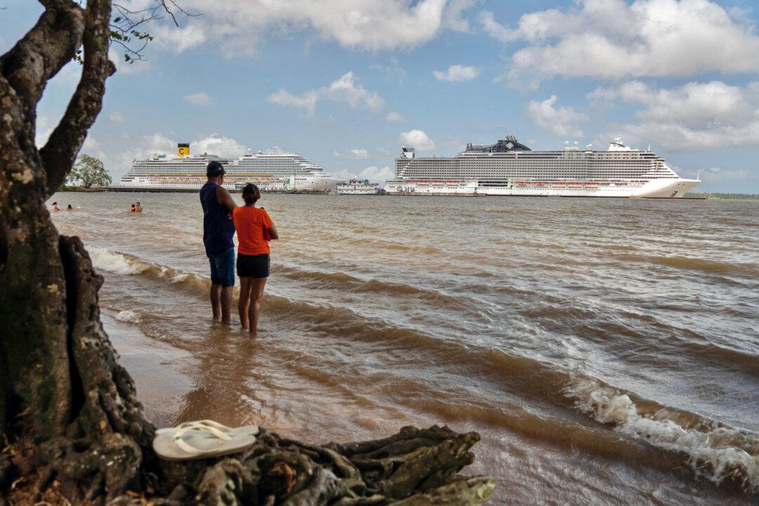 People on a beach along the Guama River watch cruise ships docked at the Port of Outeiro, which will host delegations attending the COP30 UN Climate Change Conference in Belem, Para state, Brazil, on Nov. 6, 2025. (Carlos Fabal/AFP via Getty Images)