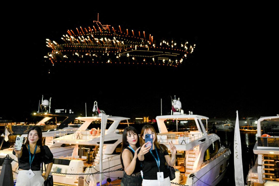 Visitors take a selfie as a light display created using drones is presented during the Qatar Boat Show, on Nov. 6, 2025. (Mahmud Hams/AFP via Getty Images)