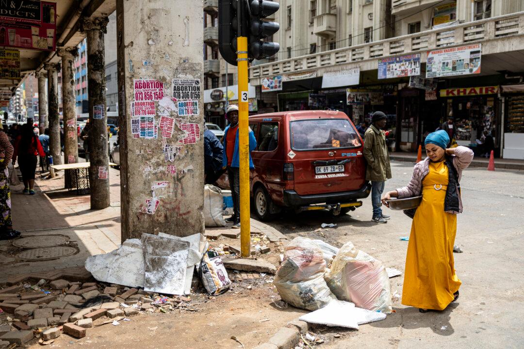 A pedestrian walks past garbage in bags on a street corner in Johannesburg on Nov. 7, 2025. The city is home to Africa's richest square mile but certain areas have fallen into disrepair, with South African President Cyril Ramaphosa describing it as “not very pleasing” and urging authorities to spruce it up as it readies to host the G20 summit. (Emmanuel Croset/AFP via Getty Images)