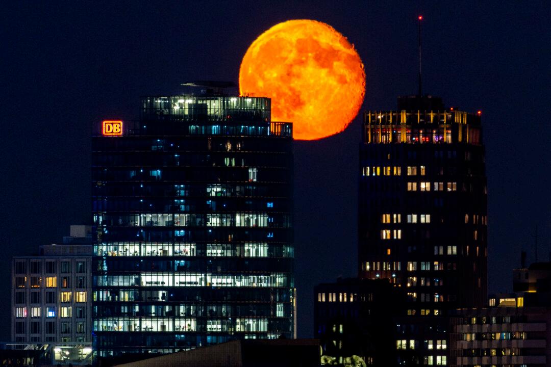 The waning gibbous moon rises over the headquarters building of German rail operator Deutsche Bahn (L) and the Daimler Chrysler Building at Berlin's Potsdamer Platz square on Nov. 7, 2025. (Odd Andersen/AFP via Getty Images)