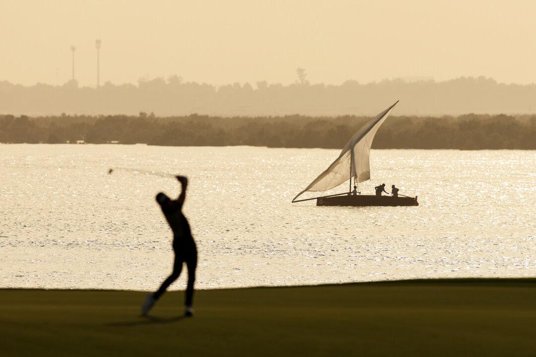 A boat passes the course as Laurie Canter of England (obscured) plays a shot on the 18th hole on day three of the Abu Dhabi HSBC Championship 2025 at Yas Links Golf Course in Abu Dhabi, United Arab Emirates, on Nov. 8, 2025. (Richard Heathcote/Getty Images)