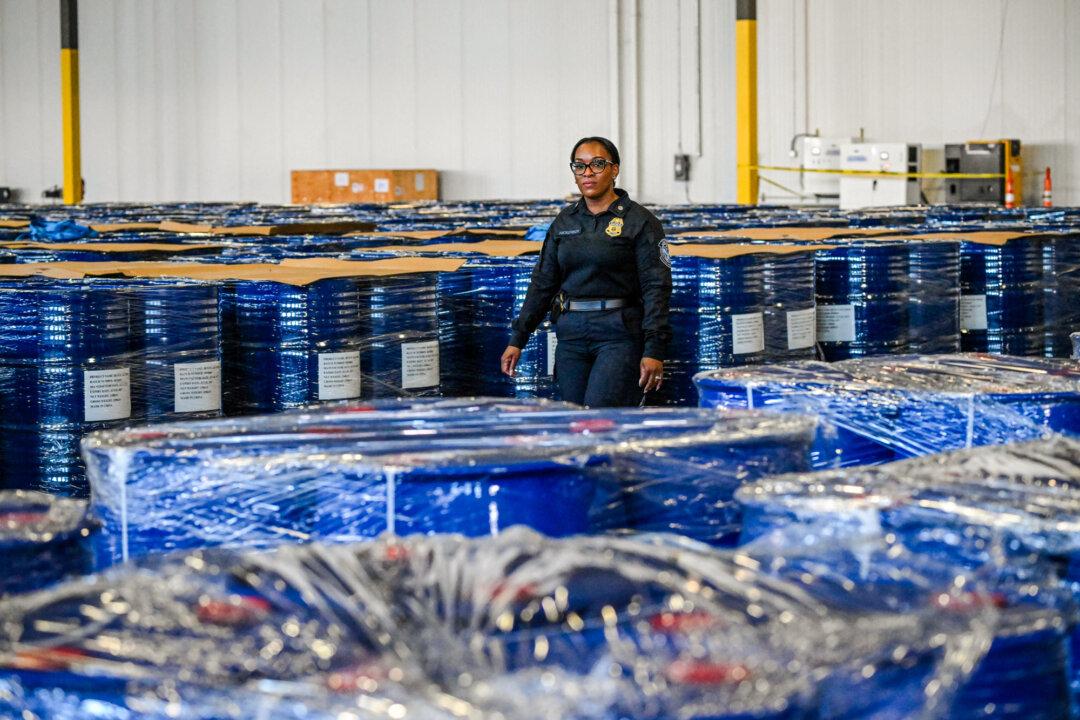 A U.S. Customs and Border Protection agent walks between barrels with chemicals used to create synthetic drugs like methamphetamine at the end of a news conference by federal authorities in Pasadena, Texas, on Sept. 3, 2025. According to U.S. Attorney for the District of Columbia Jeanine Pirro, authorities seized 300,000 kg of meth precursor chemicals sent from China and destined for Mexico's Sinaloa drug cartel. (Ronaldo Schemidt/AFP via Getty Images)
