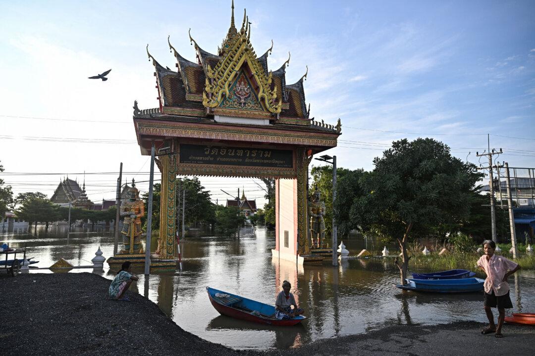 Residents gather beside boats at Wat Intharam temple as flooding inundates homes in Bang Ban district in Ayutthaya, Thailand, on Nov. 14, 2025. (Lillian Suwanrumpha/AFP via Getty Images)