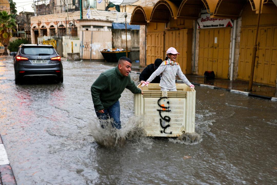 Palestinian boys push a girl inside a crate along a flooded street during heavy rain in Hebron, West Bank, on Nov. 14, 2025. (Hazem Bader/AFP via Getty Images)