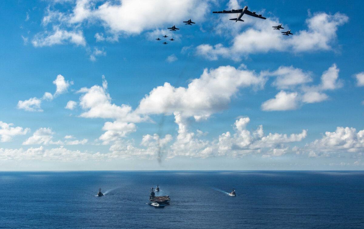 The USS Gerald R. Ford (CVN 78), front, USS Winston S. Churchill (DDG 81), right, USS Mahan (DDG 72), left, USS Bainbridge (DDG 96), and embarked Carrier Air Wing Eight F/A-18E/F Super Hornets assigned to Strike Fighter Squadrons 31, 37, 87, and 213, operates as a joint, multi-domain force with a U.S. Air Force B-52 Stratofortress, Nov. 13, 2025. (Petty Officer 3rd Class Gladjimi Balisage/U.S. Navy)