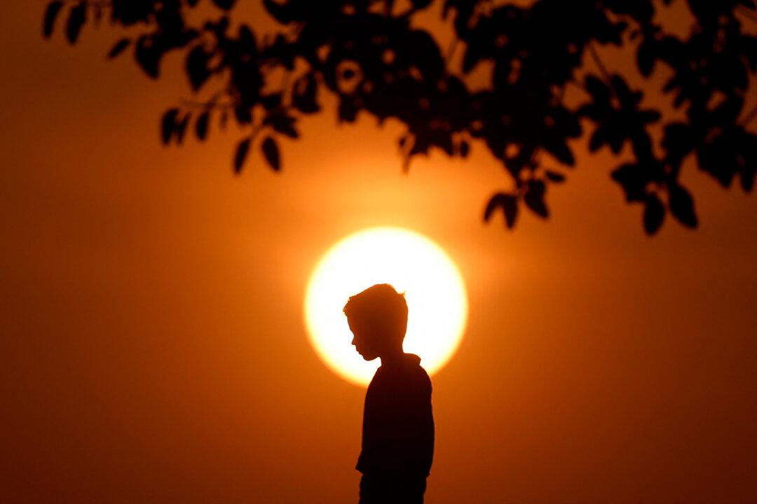A boy is silhouetted against the setting sun as he walks in Doha, Qatar, on Nov. 15, 2025. (Karim Jaafar/AFP via Getty Images)