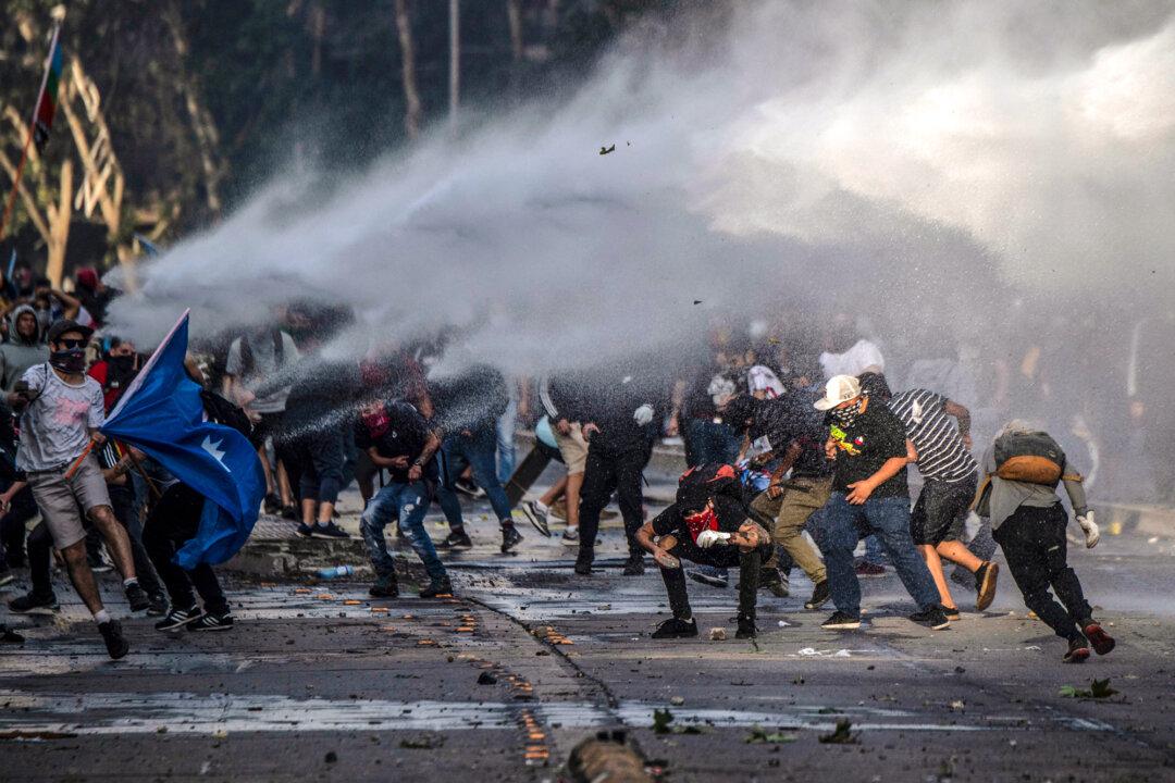 Demonstrators clash with riot police during protests against the government’s economic policies near La Moneda Palace in Santiago, Chile, on Oct. 29, 2019. The nationwide protests over inequality and the political establishment helped pave the way for Gabriel Boric, then 35, a former student protest leader, to win the presidency in 2021. (Pedro Ugarte/AFP via Getty Images)