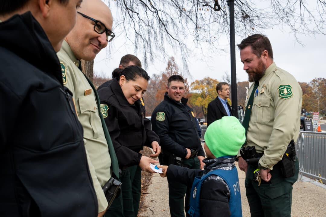 Two boys dressed as law enforcement officers give candies and a note to Nevada U.S. Forest Service rangers in Washington on Nov. 21, 2025. (Madalina Kilroy/The Epoch Times)