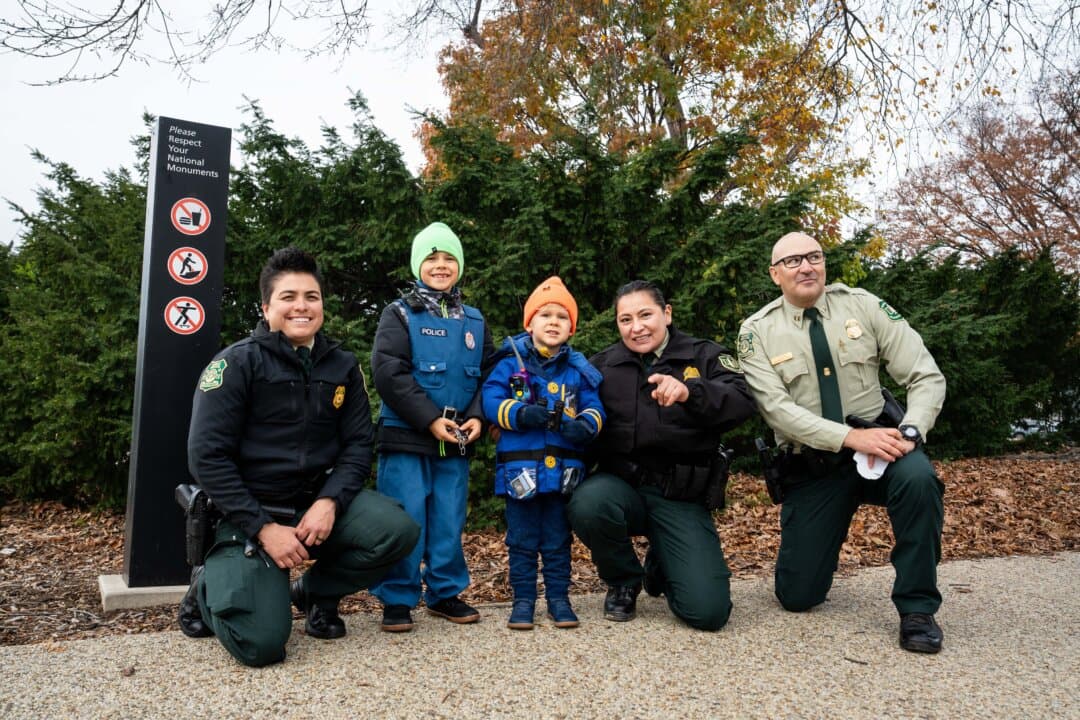Two boys dressed as law enforcement officers take a photo with Nevada U.S. Forest Service rangers in Washington on Nov. 21, 2025. (Madalina Kilroy/The Epoch Times)