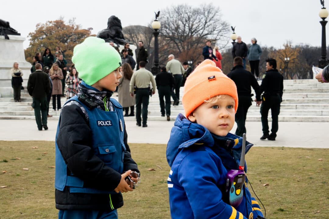 Two boys dressed as law enforcement officers give candies and a note to Nevada U.S. Forest Service rangers in Washington on Nov. 21, 2025. (Madalina Kilroy/The Epoch Times)