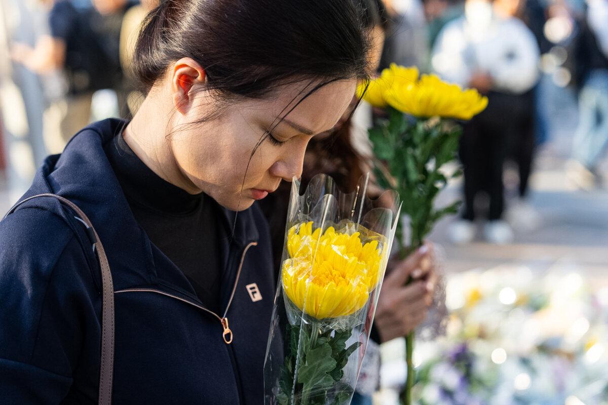 People hold flowers near the site to mourn the victims of the deadly fire at Wang Fuk Court, a residential estate in the Tai Po district of Hong Kong's New Territories, on Nov. 29, 2025. (Chan Long Hei/AP Photo)