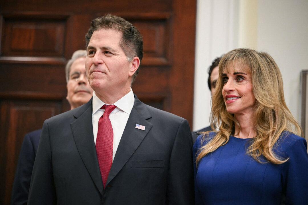 Michael Dell (L) and his wife, Susan, look on during an announcement of their $6.25 billion donation to “Trump Accounts” at the White House on Dec. 2, 2025. The donation would expand coverage to children who do not qualify for the federal $1,000 newborn contribution to the tax-advantaged accounts. (Andrew Caballero-Reynolds/AFP via Getty Images)