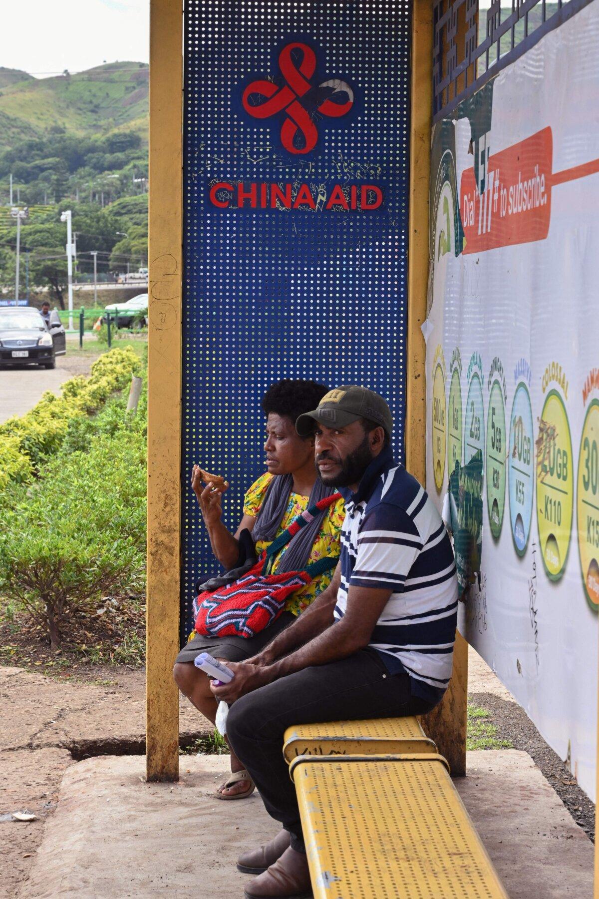 This picture taken on May 18, 2023 shows people sitting at a bus shelter in Port Moresby. (Adek Berry/AFP via Getty Images)