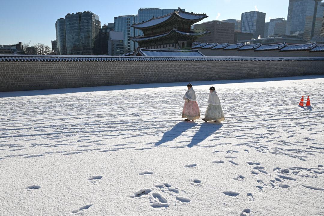 Visitors wearing traditional hanbok dresses walk after the season's first snowfall on the snow-covered grounds of Gyeongbokgung Palace in Seoul, South Korea, on Dec. 5, 2025. (Jung Yeon-je/AFP via Getty Images)