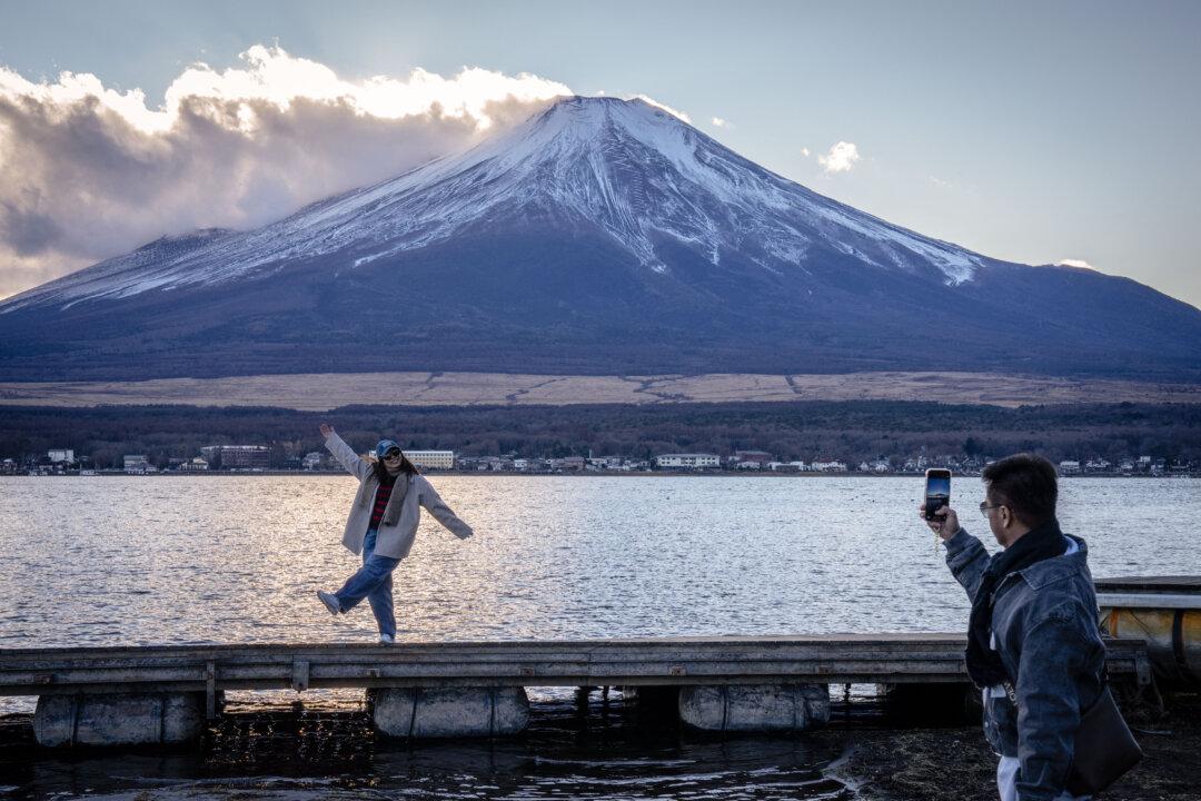 People take photographs in front of Mount Fuji at Lake Yamanakako in snow in Yamanakako, Japan, on Dec. 5, 2025. (Yuichi Yamazaki/AFP via Getty Images)