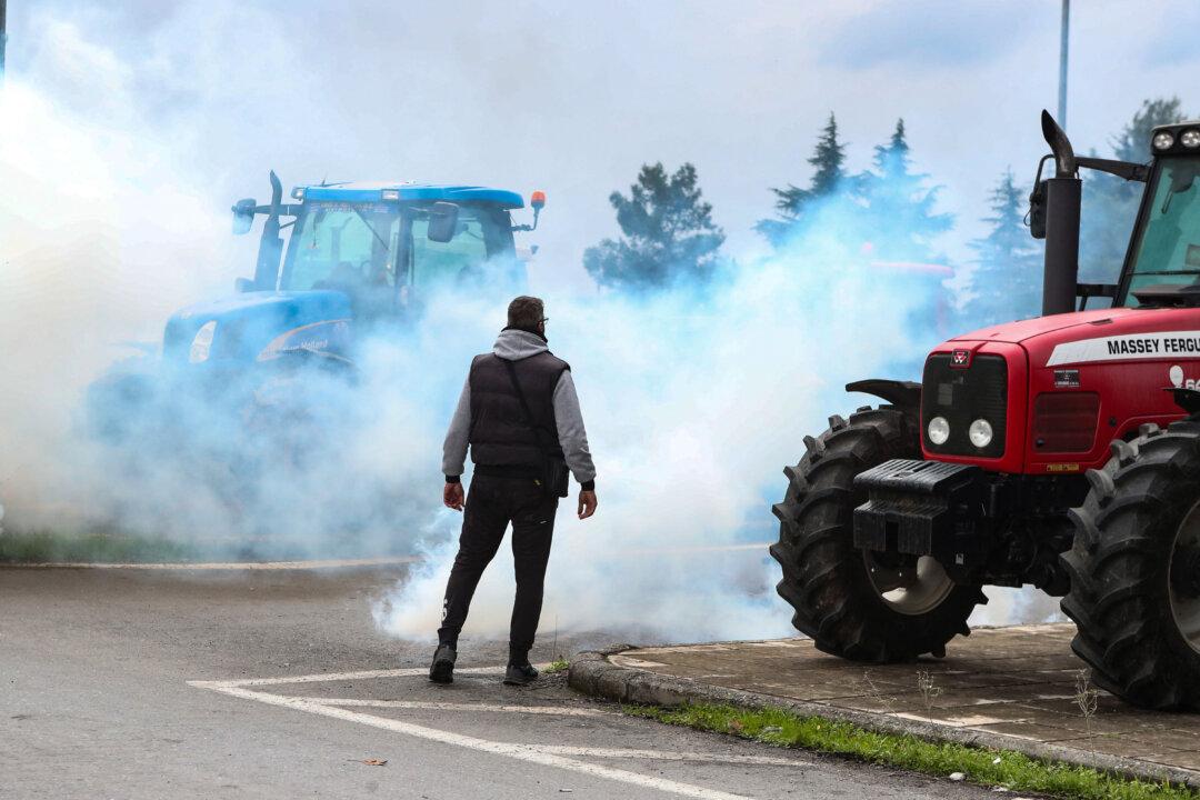 A protester stands amid the smoke from teargas fired by riot police as farmers block the road leading to the airport with their tractors during a protest over the reduced and delayed payment of European Union subsidies, in Thessaloniki, Greece, on Dec. 5, 2025. (AFP via Getty Images)