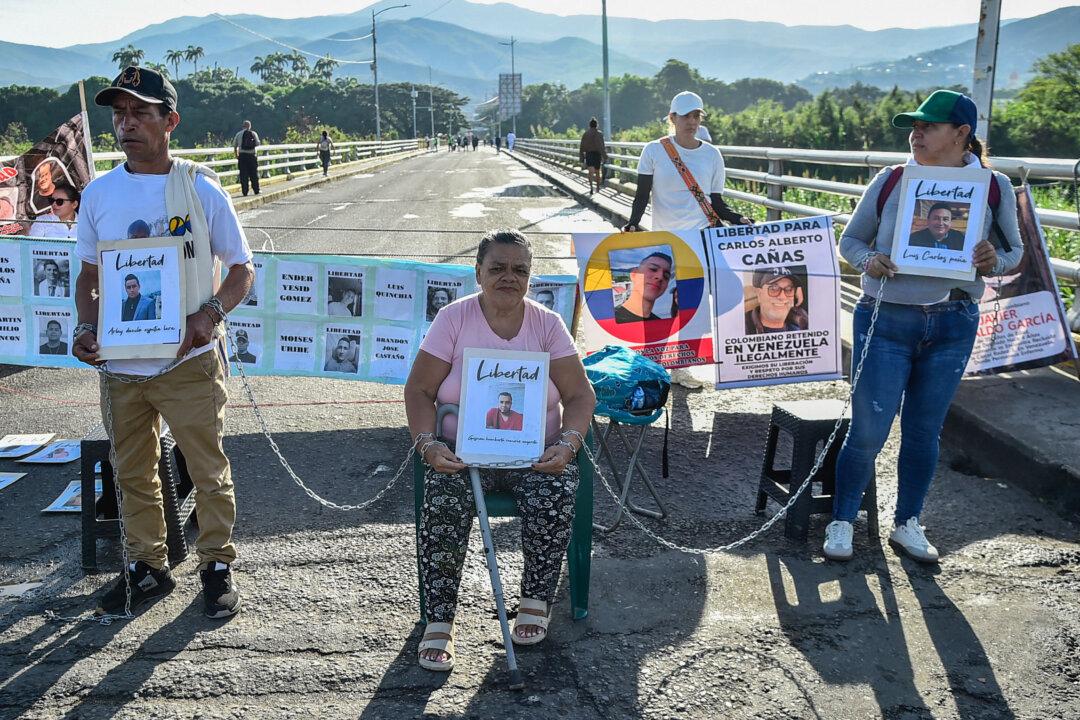 Chained relatives of Colombian nationals detained in Venezuela hold pictures while blocking the international Simon Bolivar border bridge between Colombia and Venezuela to demand their release, in Villa del Rosario, Colombia, on Dec. 5, 2025. (Schneyder Mendoza/AFP via Getty Images)