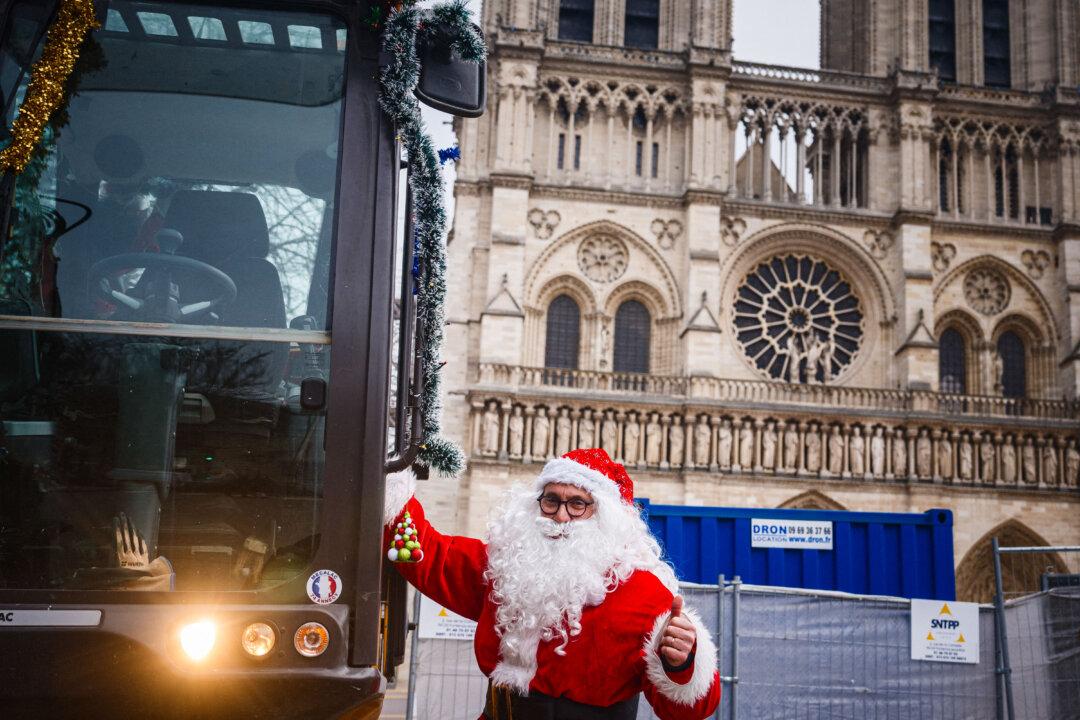A man dressed as Santa Claus gestures a thumbs-up as he climbs onto an excavator in front of Notre Dame Cathedral in Paris on Dec. 5, 2025. (Dimitar Dillkoff/AFP via Getty Images)