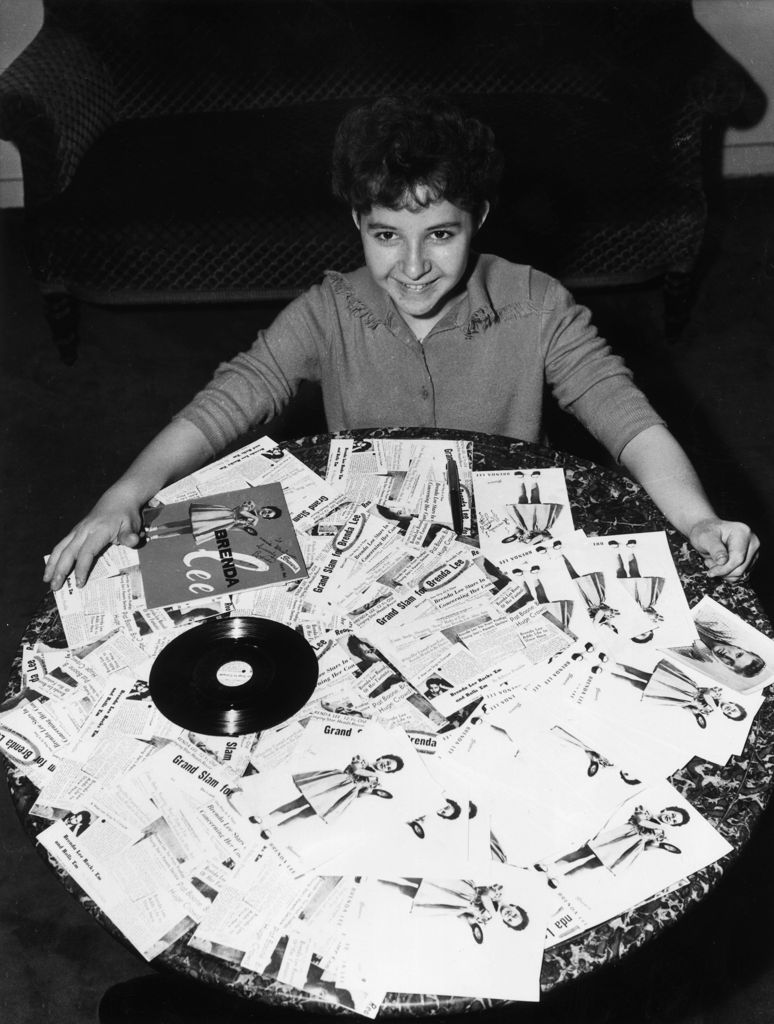The young American pop/country singer Brenda Lee sits behind a table covered with copies of her album, "Brenda Lee," circa 1960. (Hulton Archive/Getty Images)