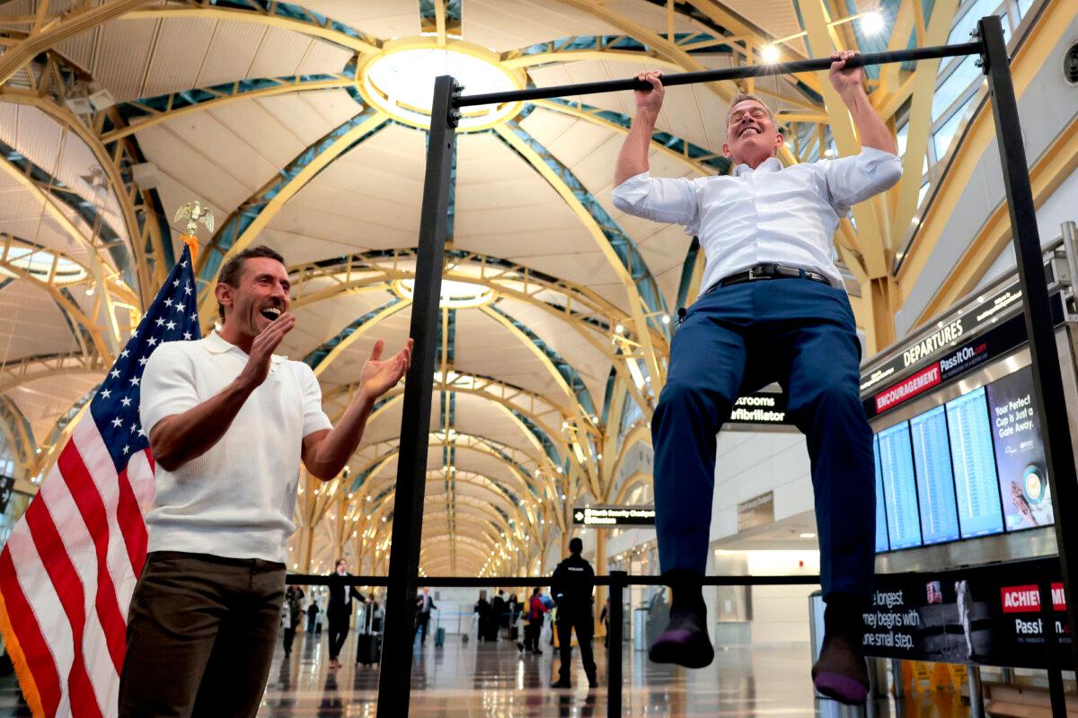 Influencer Dr. Paul Saladino watches Transportation Secretary Sean P. Duffy do pull-ups after a press conference discussing the launch of the "Make Travel Family Friendly Again" campaign at Ronald Reagan Washington National Airport in Arlington, Va., on Dec. 8, 2025. (Heather Diehl/Getty Images)