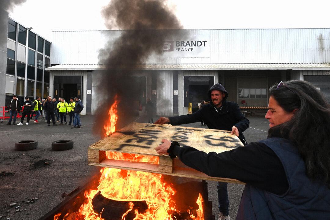 Employees throw a sign reading “93 dismissed employees at Christmas” into a fire at the Brandt factory, in Vendome, France, on Dec. 11, 2025 following a court verdict. The court ordered liquidation of the century-old home-appliance group Brandt, a flagship of French industry that has been in serious trouble since it was placed under court-supervised restructuring, the president of the Centre-Val de Loire region told AFP. (Jean-Francois Monier/AFP via Getty Images)