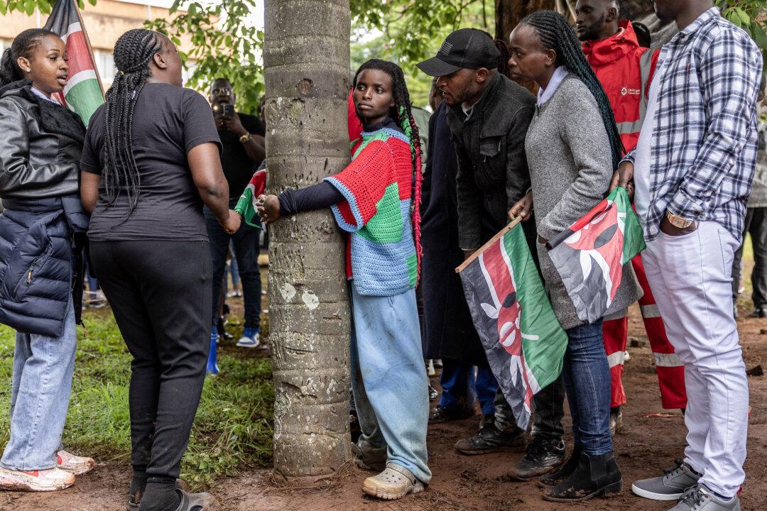 Climate activist Truphena Muthoni, 22, surrounded by friends and well wishers, leans on a tree as she set a new Guinness World Record after hugging a tree for 72 hours without eating or sleeping, shattering her previous 48-hour record, in Nyeri, Kenya, on Dec. 11, 2025. (Simon Maina/AFP via Getty Images)