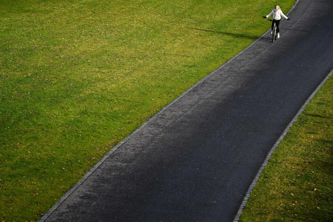 A woman rides a bicycle along the embankment of the Main river as the temperature reached 10 degrees Celsius in Frankfurt am Main, Germany, on Dec. 11, 2025. (Kirill Kudryavtsev/AFP via Getty Images)