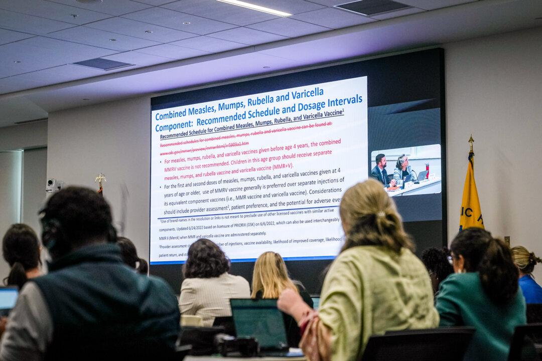 A slide showing proposed changes to the MMR vaccine schedule and dose intervals is displayed during an Advisory Committee on Immunization Practices meeting in Atlanta on Sept. 18, 2025. The two U.S. measles vaccinations are MMR and MMRV; earlier this year, the CDC stopped recommending MMRV for younger children because of a higher risk of febrile seizures. (Elijah Nouvelage/Getty Images)
