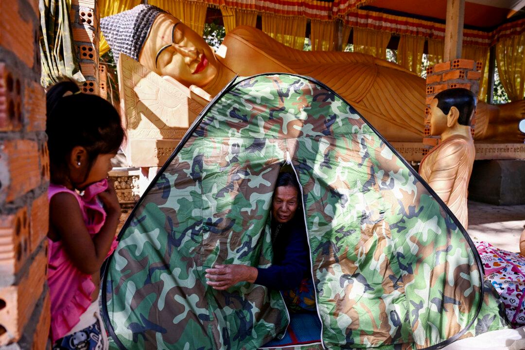 A displaced resident sits in a tent in front of a Buddha statue at a temporary camp set up in a pagoda in Cambodia's Siem Reap province on Dec. 12, 2025, amid clashes along the Cambodia–Thailand border. (Tang Chhin Sothy/AFP via Getty Images)
