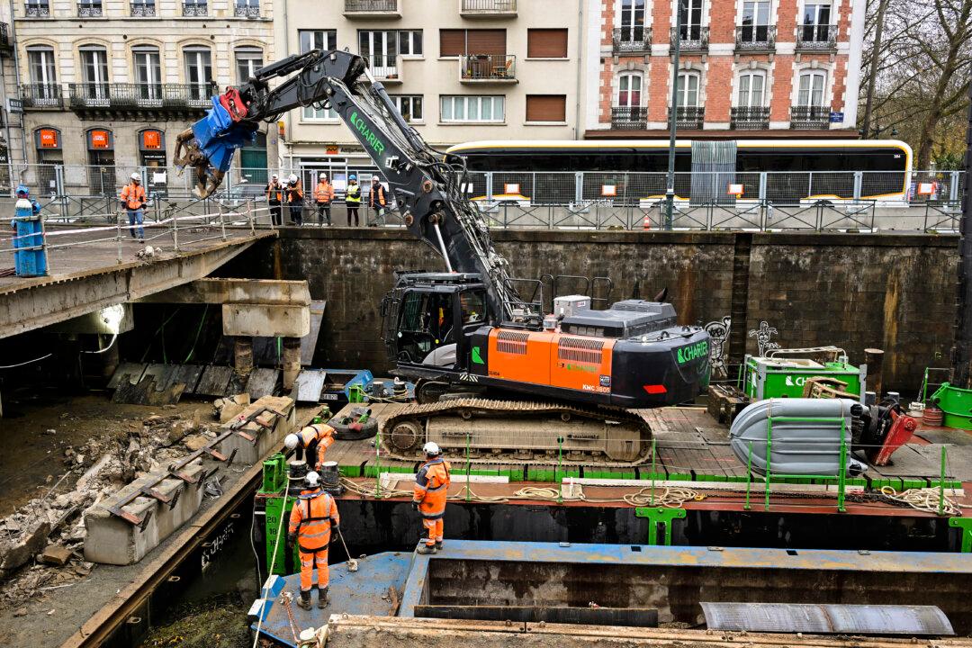 Workers use an excavator, mounted on a barge, to chip away the slab of a car park and uncover the Vilaine river, in the city centre of Rennes, France, on Dec. 12, 2025. (Damien Meyer/AFP via Getty Images)