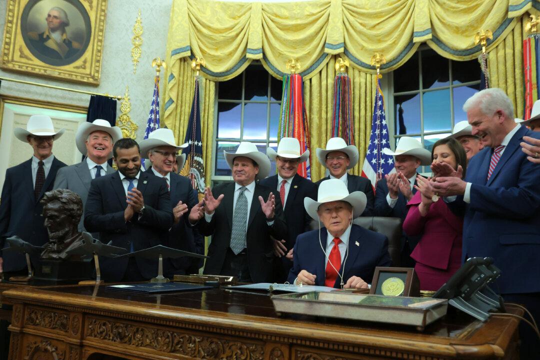 President Donald Trump puts on a hat given to him by the 1980 U.S. Olympic men’s ice hockey team as Trump honors the team in the Oval Office of the White House on Dec. 12, 2025. Trump honored the ‘Miracle on Ice’ team, who defeated the Soviet Union and went on to win the 1980 Gold medal in Ice Hockey, by signing a bill to award the players congressional gold medals. (Anna Moneymaker/Getty Images)
