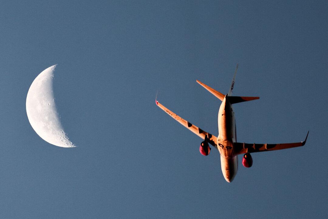 An Air Algerie airliner, with the moon seen in the background, flies above Marseille, France, on Dec. 13, 2025. (Thibaud Moritz/AFP via Getty Images)