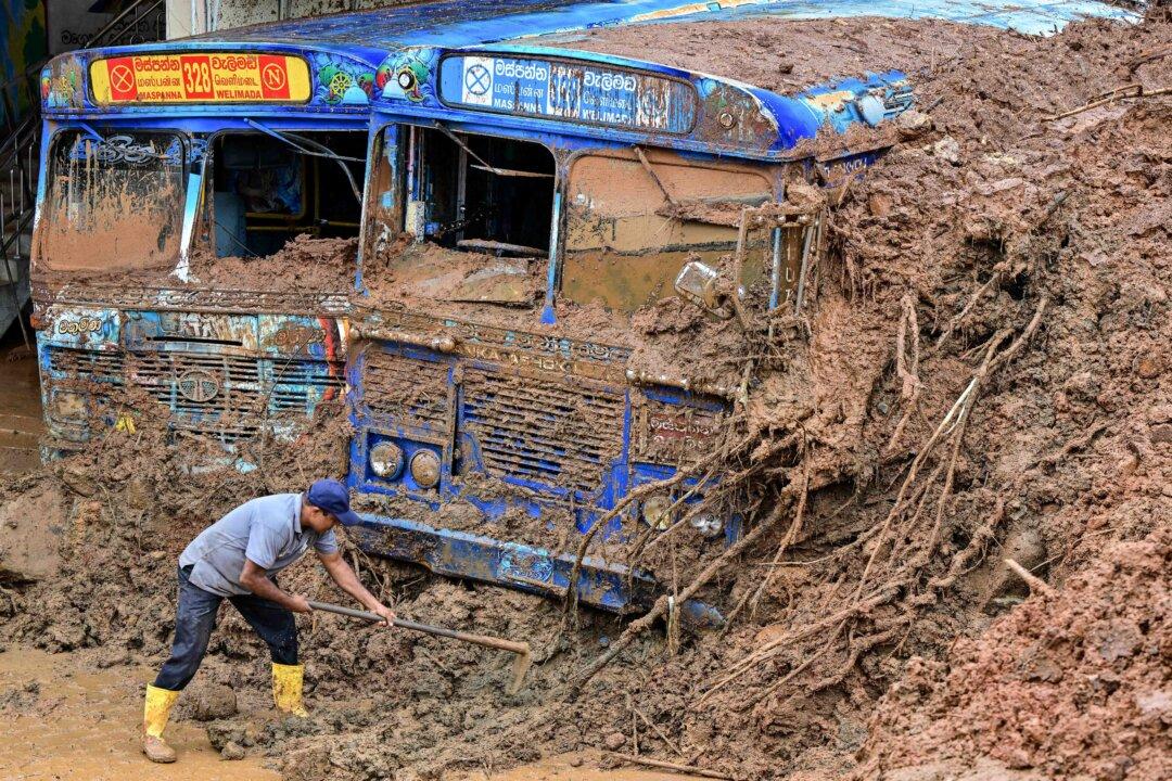 A worker removes mud accumulated around buses near a landslide-affected area in the aftermath of Cyclone Ditwah, in Maspanna, Sri Lanka, on Dec. 13, 2025. Tropical storms and monsoon rains have pummeled Southeast and South Asia in December, triggering landslides and flash floods that killed at least 639 people in Sri Lanka and nearly 1,000 in Indonesia. (Ishara S. Kodikara/AFP via Getty Images)