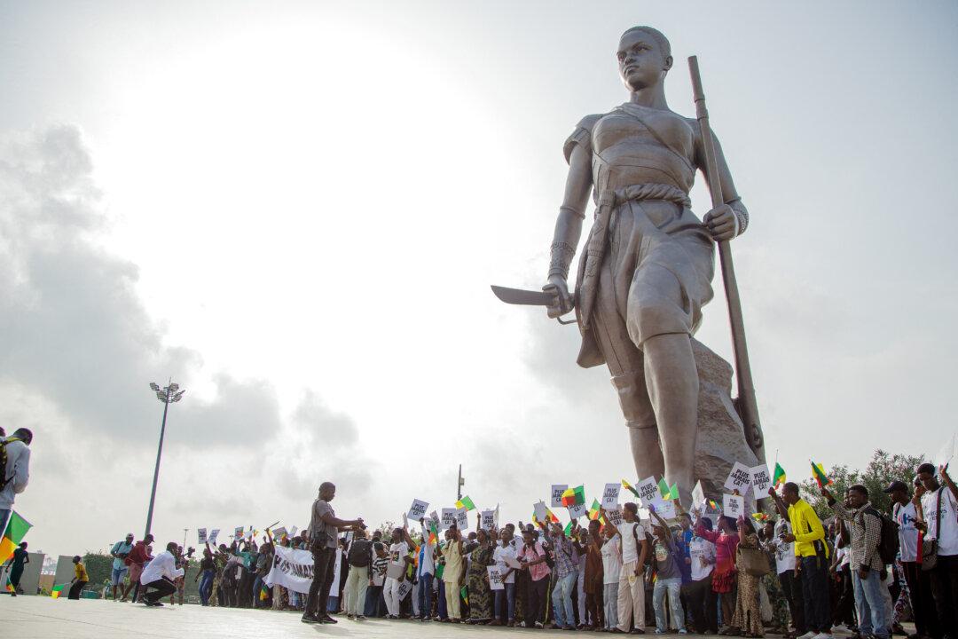 Young students and influencers march with the Beninese flag and signs reading Never Again on their foreheads in the Esplanade des Amazones in Cotonou in Benin, on Dec. 13, 2025. (Abadjayé Justin Sodogandji/Hans Lucas/AFP via Getty Images)