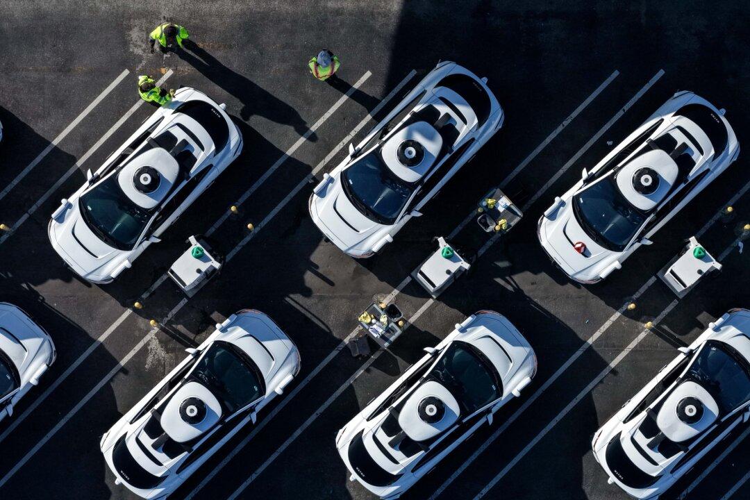 Waymo robotaxis sit parked at a facility in San Francisco on Dec. 8, 2025. Self-driving taxi company Waymo said it is voluntarily recalling software in its autonomous vehicles after Texas officials documented at least 19 incidents this school year in which the cars illegally passed stopped school buses, including while students were getting on or off. (Justin Sullivan/Getty Images)