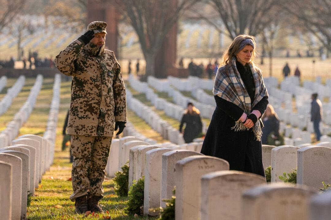 Participants reflect on the headstones before them on Wreaths Across America Day at Arlington National Cemetery in Arlington, Va., on Dec. 13, 2025. Thousands of participants gathered before sunrise for the annual holiday season event honoring fallen service members. (Allison Robbert/Getty Images)