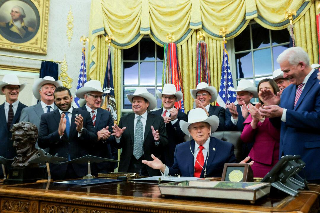 President Donald Trump puts on a hat given to him by the 1980 U.S. Olympic men’s ice hockey team as Trump honors the team in the Oval Office at the White House on Dec. 13, 2025. Trump honored the “Miracle on Ice” team, who defeated the Soviet Union and went on to win the 1980 Gold medal in Ice Hockey, by signing a bill to award the players congressional gold medals. (Anna Moneymaker/Getty Images)
