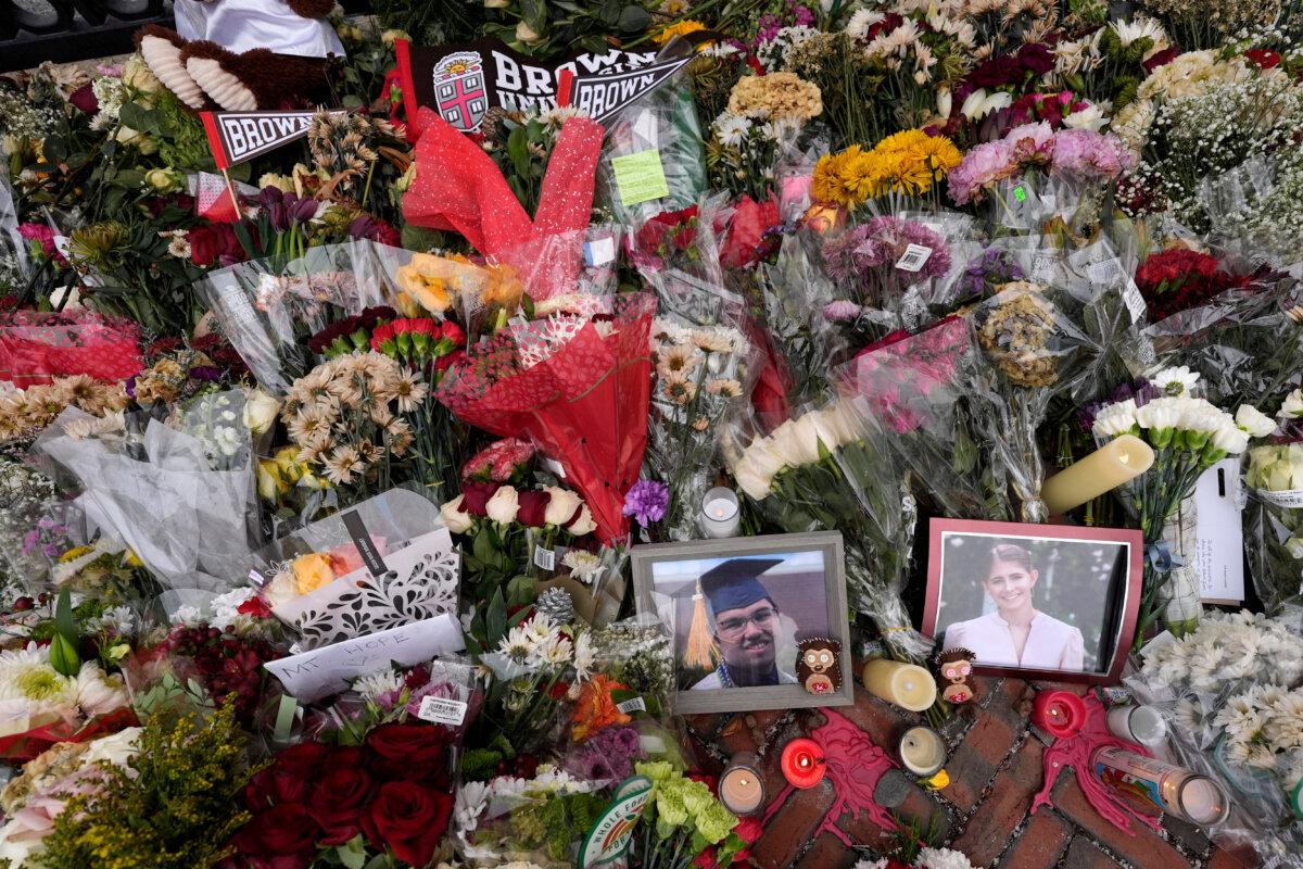 Photos of Brown University shooting victims Mukhammad Aziz Umurzokov (L) and Ella Cook (R) amongst flowers at a makeshift memorial at the school's Van Wickle Gate in Providence, R.I., on Dec. 17, 2025. (Robert F. Bukaty/AP Photo)