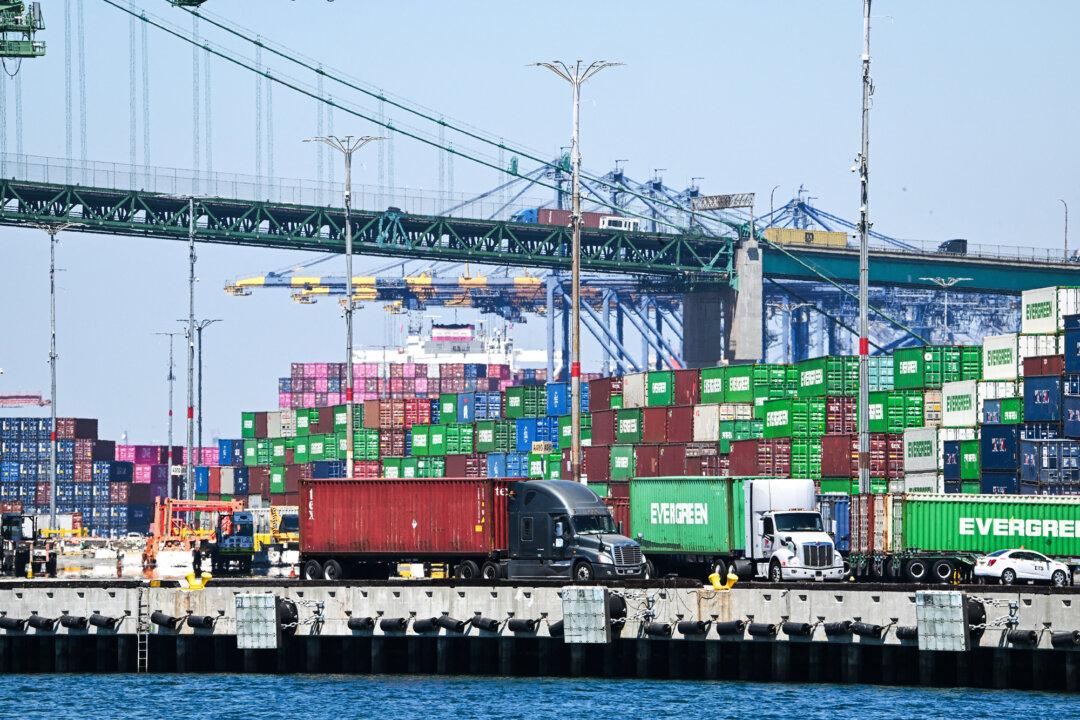 Container trucks pass stacks of containers at the Port of Los Angeles on July 31, 2025. According to officials, it is the nation’s busiest port and nearly 20,000 licensed drivers work there daily, about half of whom call at least once per week. (Robyn Beck/AFP via Getty Images)