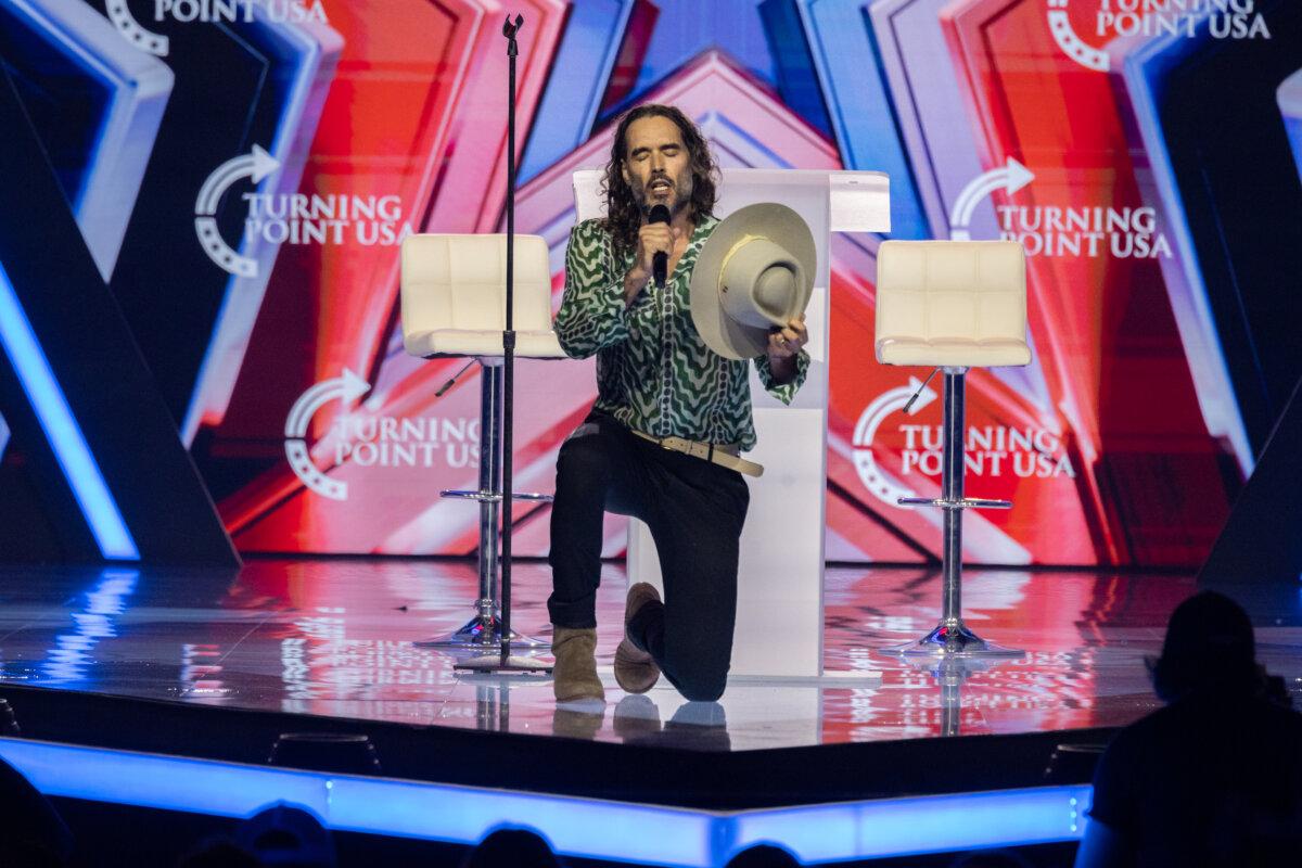 Russell Brand prays at Turning Point USA's AmericaFest in Phoenix on Dec. 18, 2025. (John Fredricks/The Epoch Times)