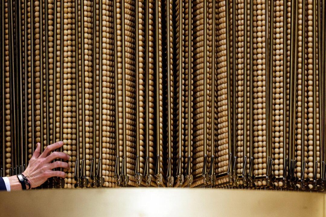 Officials check the numbers next to the rotating drum during the draw of Spain's Christmas lottery “El Gordo” (the Fat One) at the Royal Theater in Madrid on Dec. 22, 2025. (Oscar Del Pozo Cañas/AFP via Getty Images)