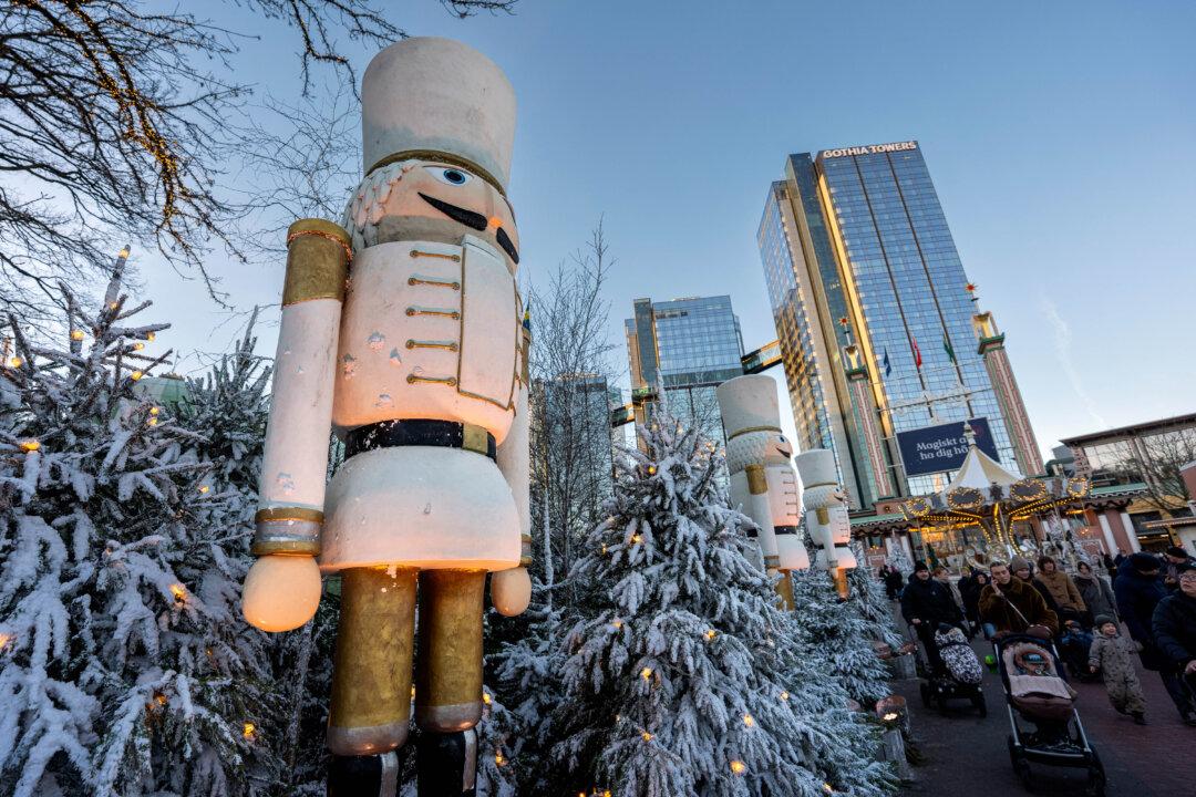 Visitors stroll past a giant Nutcracker figure and snow-covered Christmas trees at the Christmas market in Liseberg Park in Gothenburg, Sweden, on Dec. 22, 2025. (Bjorn Larsson Rosvall/TT News Agency/AFP via Getty Images)