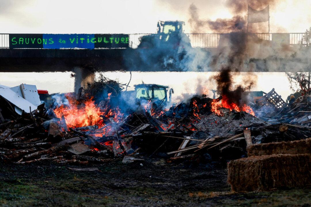 Tractors, along with burning wood and hay, block the A63 highway in Cestas, France, on Dec. 22, 2025, during a farmers protest against the government's mandatory culling of cattle affected by lumpy skin disease. (Romain Perrocheau/AFP via Getty Images)
