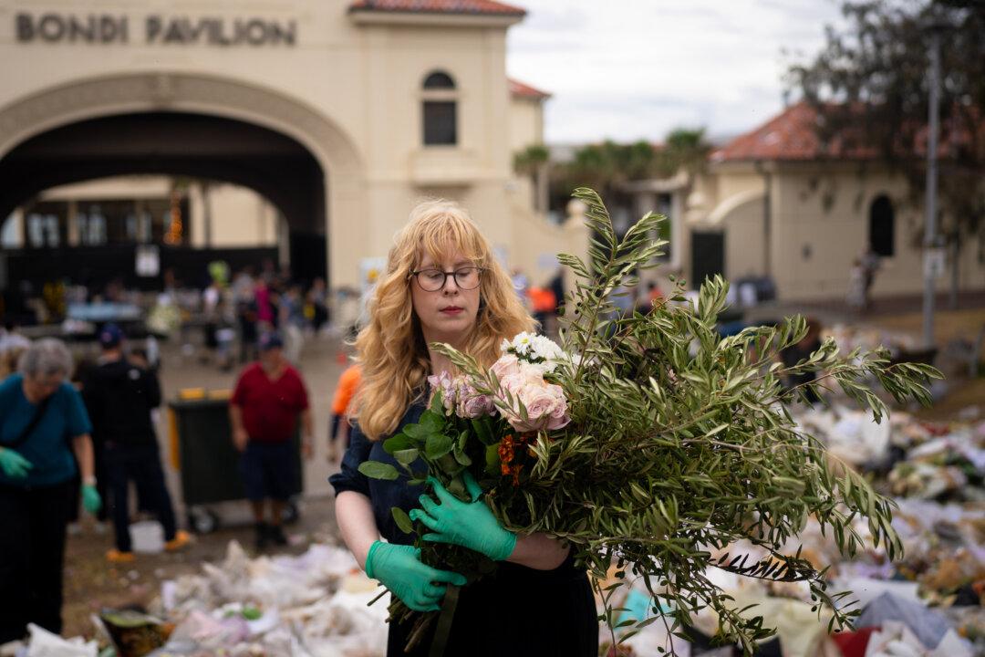 Rebecca Kummerfeld helps clear flowers and notes honoring victims and survivors of the deadly Bondi Beach mass shooting at Bondi Pavilion in Sydney on Dec. 22, 2025. Life is slowly returning to normal at Bondi Beach, with people from all walks of life still paying respects as grief and funerals gave way to quiet commemorations. (Audrey Richardson/Getty Images)