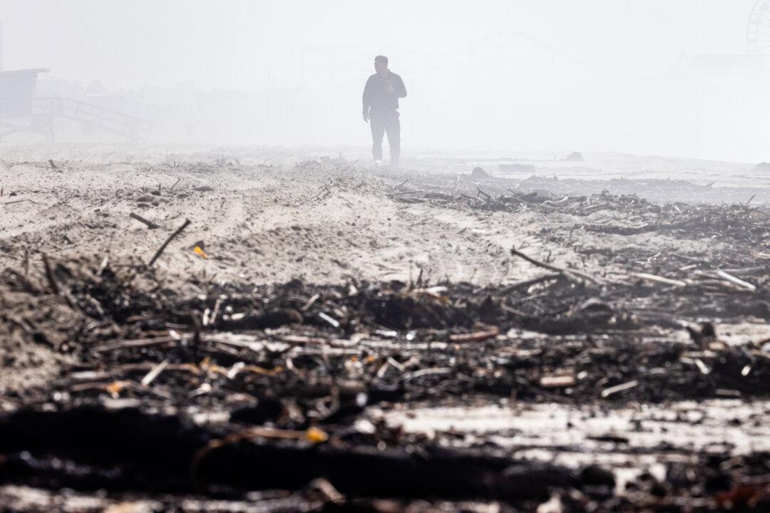 A man walks over debris left from the Palisades Fire and heavy rains in Santa Monica, Calif., on Feb. 27, 2025. (John Fredricks/The Epoch Times)