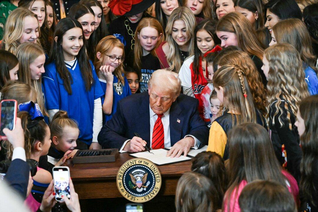 President Donald Trump, surrounded by young women and girls, signs the No Men in Women's Sports Executive Order into law in the East Room of the White House on Feb. 5, 2025. (Andrew Caballero-Reynolds/AFP via Getty Images)