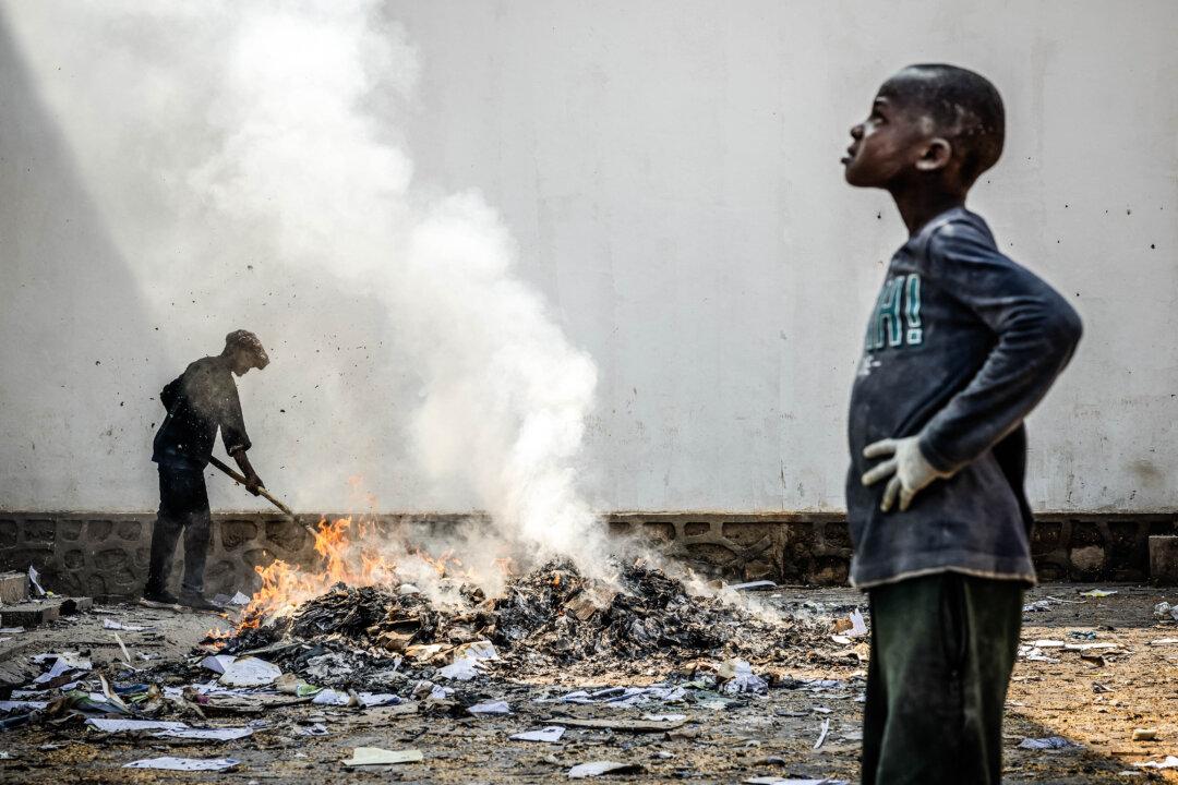 A man uses a stick to sift through the smoldering remains of boxes at the World Food Programme warehouse in Bukavu, Democratic Republic of Congo, on Feb. 21, 2025, after Rwanda-backed M23 fighters seized control of two major eastern cities in the country. (Luis Tato/AFP via Getty Images)