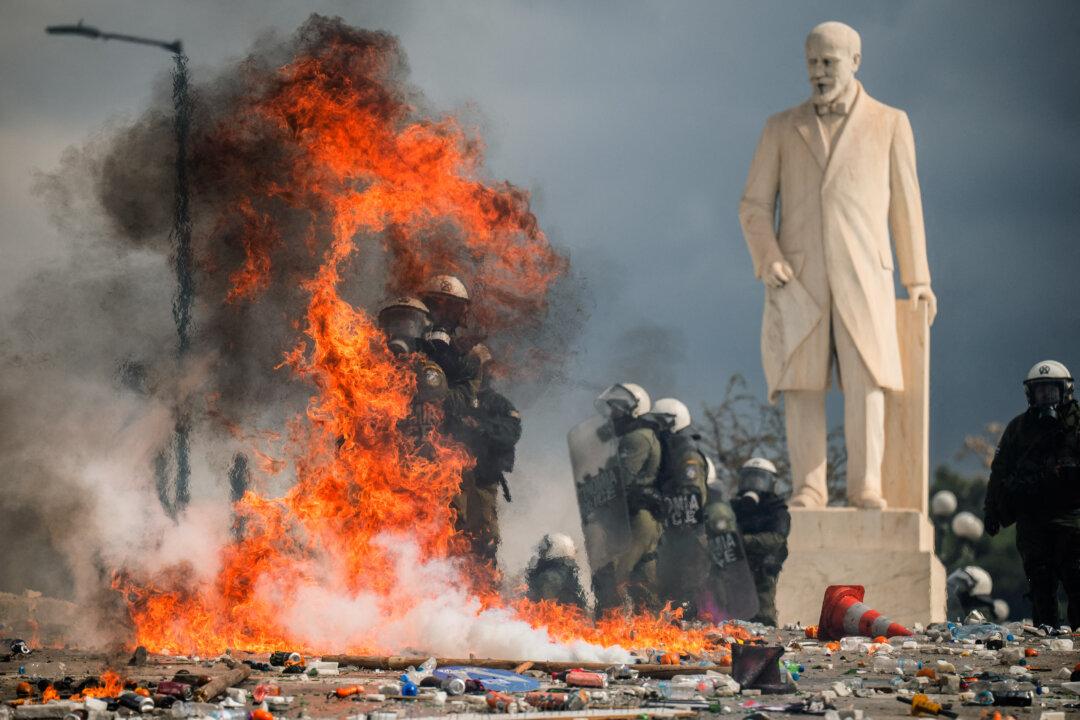 Riot police officers stand next to the statue of Eleftherios Venizelos as they take cover from Molotov cocktails thrown by demonstrators as clashes break out during a rally as part of a general strike called by unions to mark the second anniversary of the country's worst rail tragedy that left 57 dead on Feb. 28, 2023, in front of the Greek parliament in Athens on Feb. 28, 2025. The unions have called for a general strike in the private and public sectors which will particularly affect transport. (Angelos Tzortzinis/AFP via Getty Images)